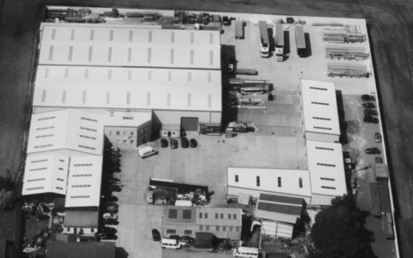 A black and white photo of a large warehouse offering metal solutions and laser cutting services.