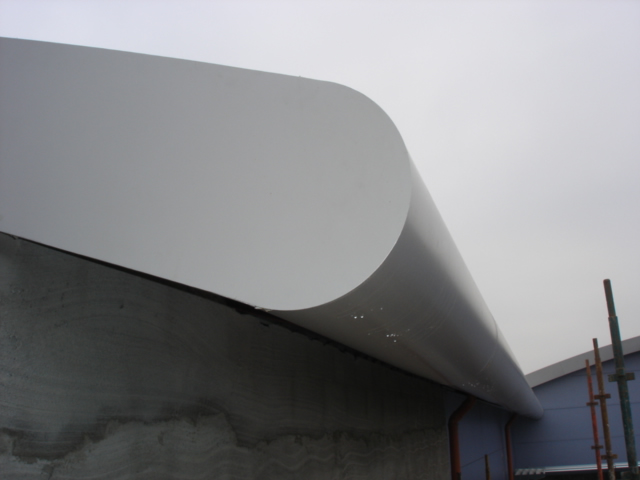 A white building with a curved roof, constructed by top metal manufacturers.