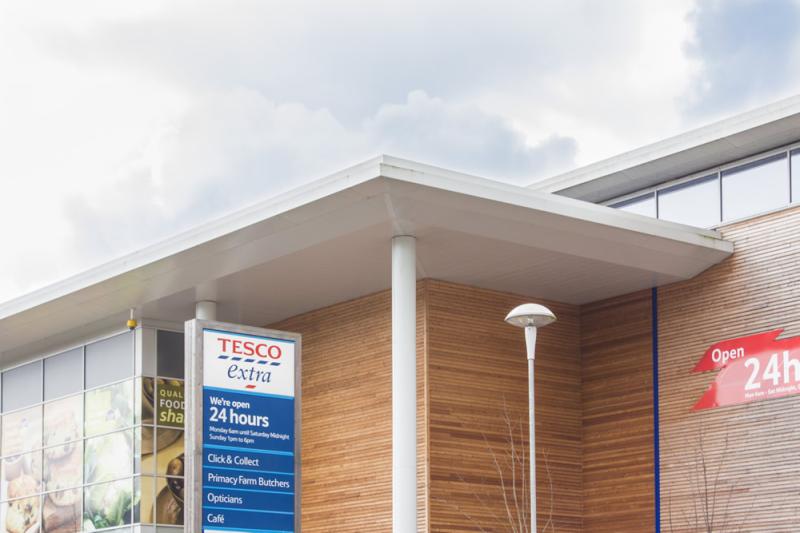 A tesco store with a sign on the front offering laser cutting services.