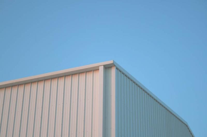 A white building against a blue sky, providing metal solutions and laser cutting services.