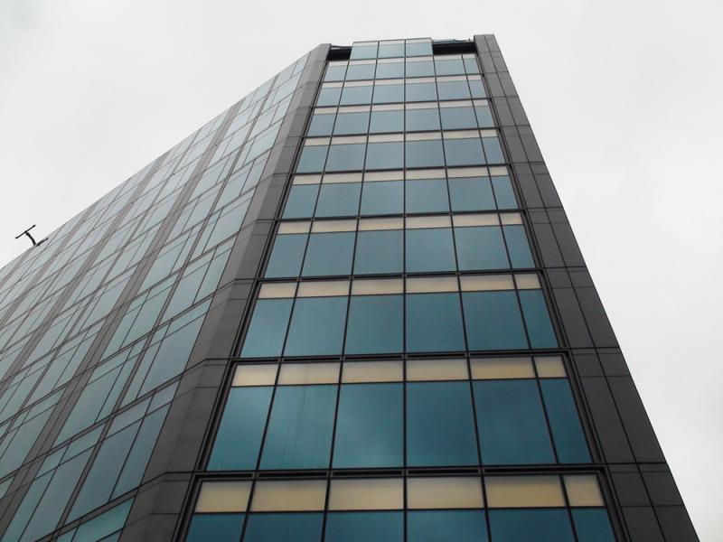 A building with many windows providing metal solutions, under a cloudy sky.
