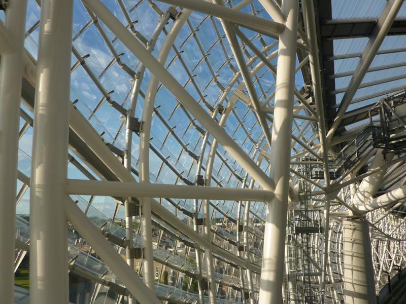 A glass structure showcasing a stunning view of the sky and complemented by expertly crafted metal sheets produced through laser cutting services.