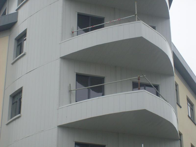 A white building with balconies made of metal sheets.