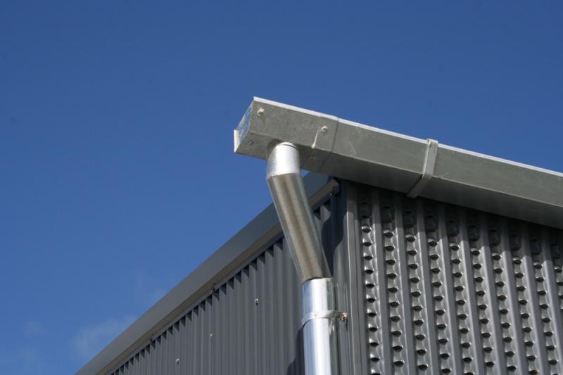 A metal pipe, manufactured by a steel manufacturer, is attached to the side of a building.