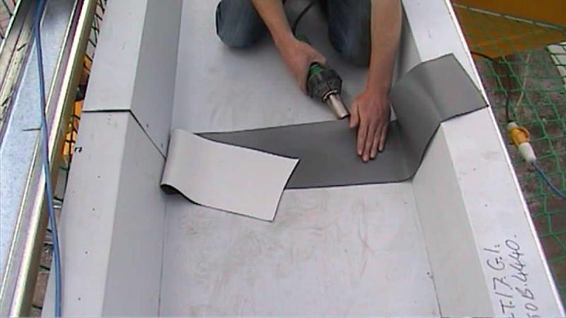 A man is working on a roof with a piece of metal tape.