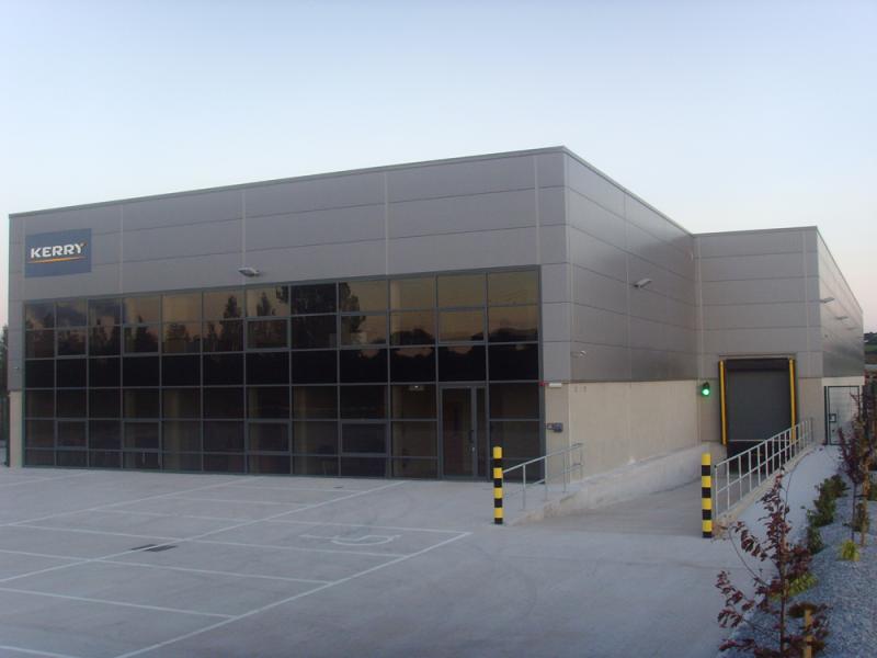 A grey building with laser cutting services and a parking lot.