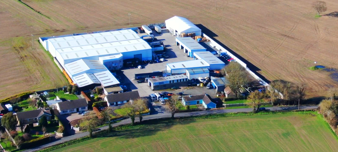 An aerial view of a farm with a large building featuring steel manufacturers.