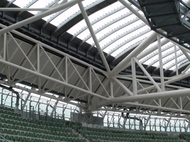 A stadium with a roof made of metal sheets and green seats.
