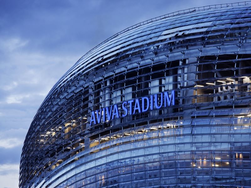 A stadium with a blue sign on it at dusk, showcasing the expertise of steel manufacturers.